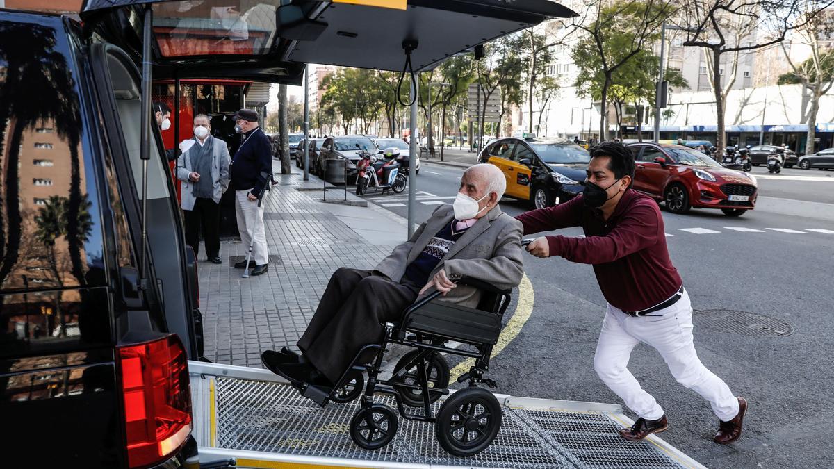 Frank, taxista, ayuda a bajar a Álvarez padre de su taxi adaptado. Al fondo, su hijo espera para entrar en la sucursal bancaria.