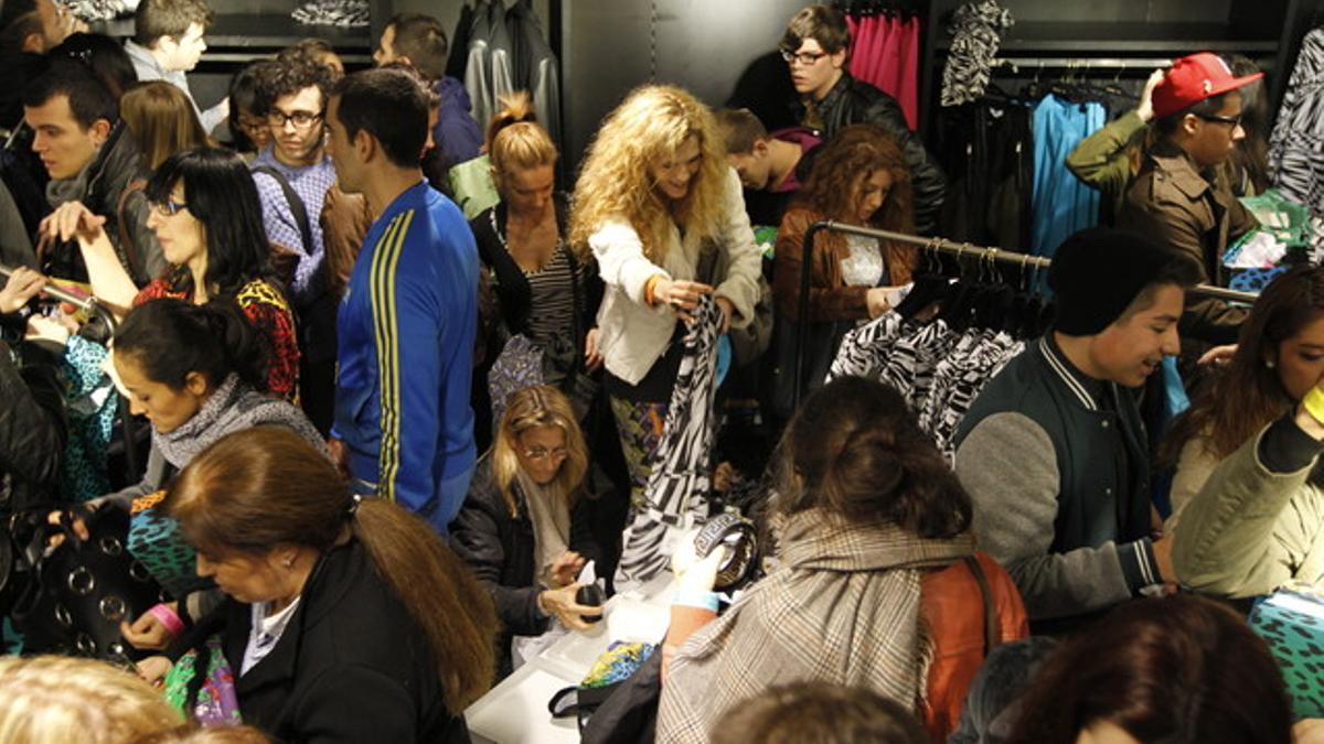 Clientes miran las prendas de Versace en la tienda de H&amp;M en el Paseo de Gracia, este jueves, en Barcelona.