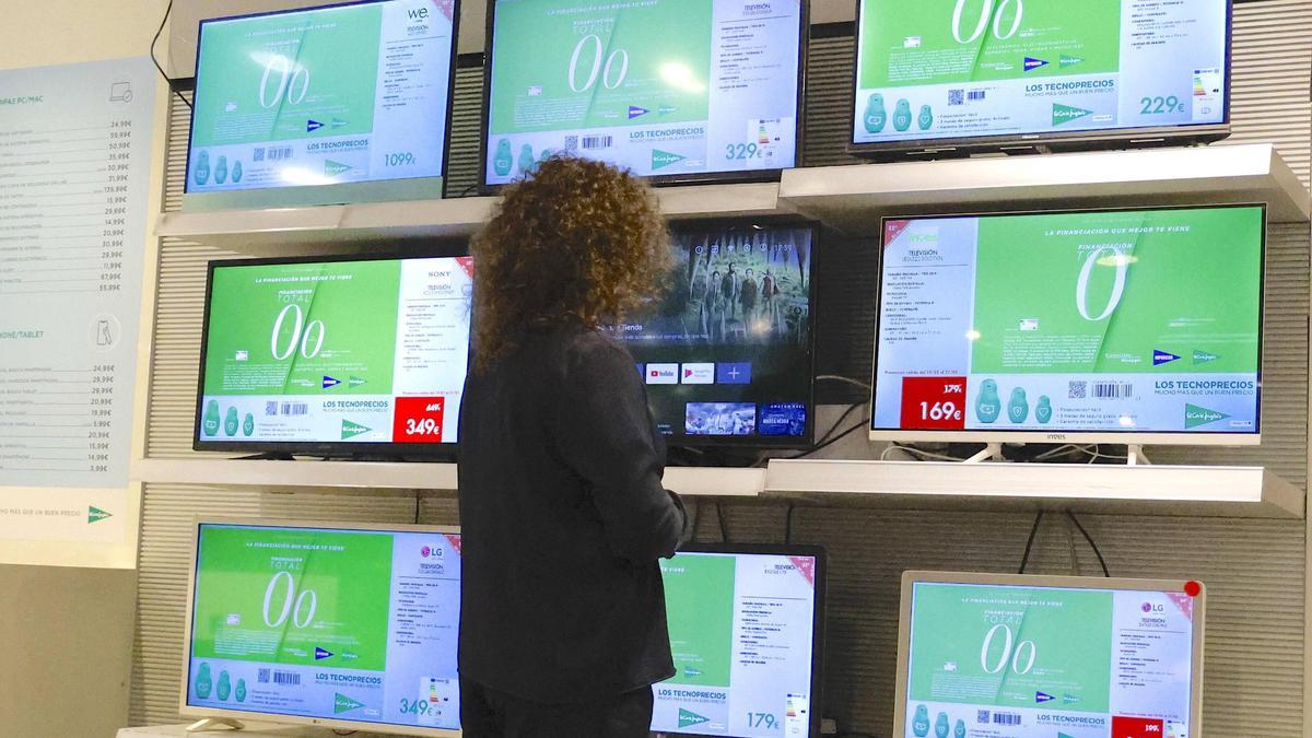 Una mujer observa televisiones de pequeño formato en un establecimiento comercial en Santiago