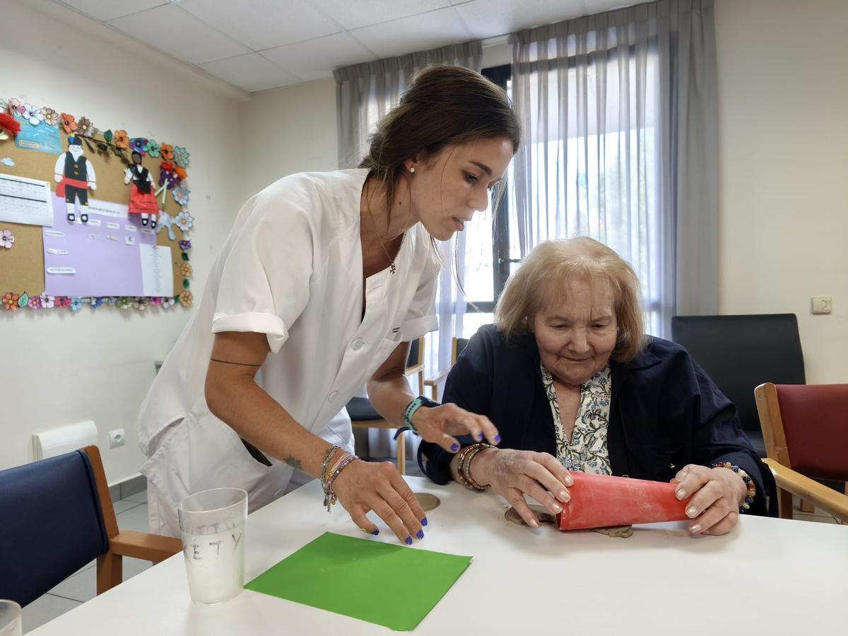 Por la izquierda, la terapeuta ocupacional, Claudia Muñiz, trabaja con la usuaria, Kety Hevia, en el centro de día de Pola de Siero.