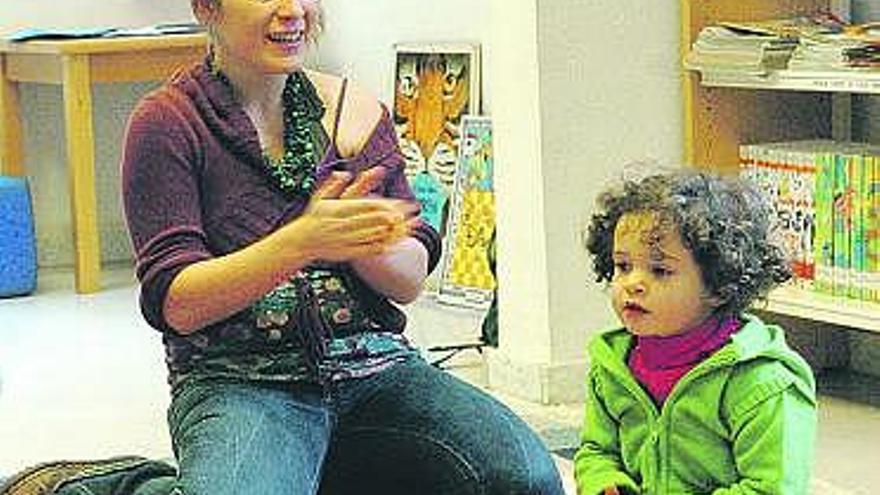 Vanessa Peña, junto a una niña, en la Biblioteca de La Corredoria.