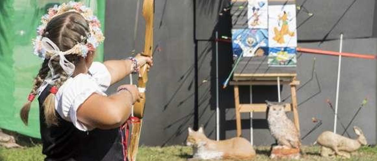 Una niña tira al blanco con un arco en la fiesta medieval. // Paula Fariña