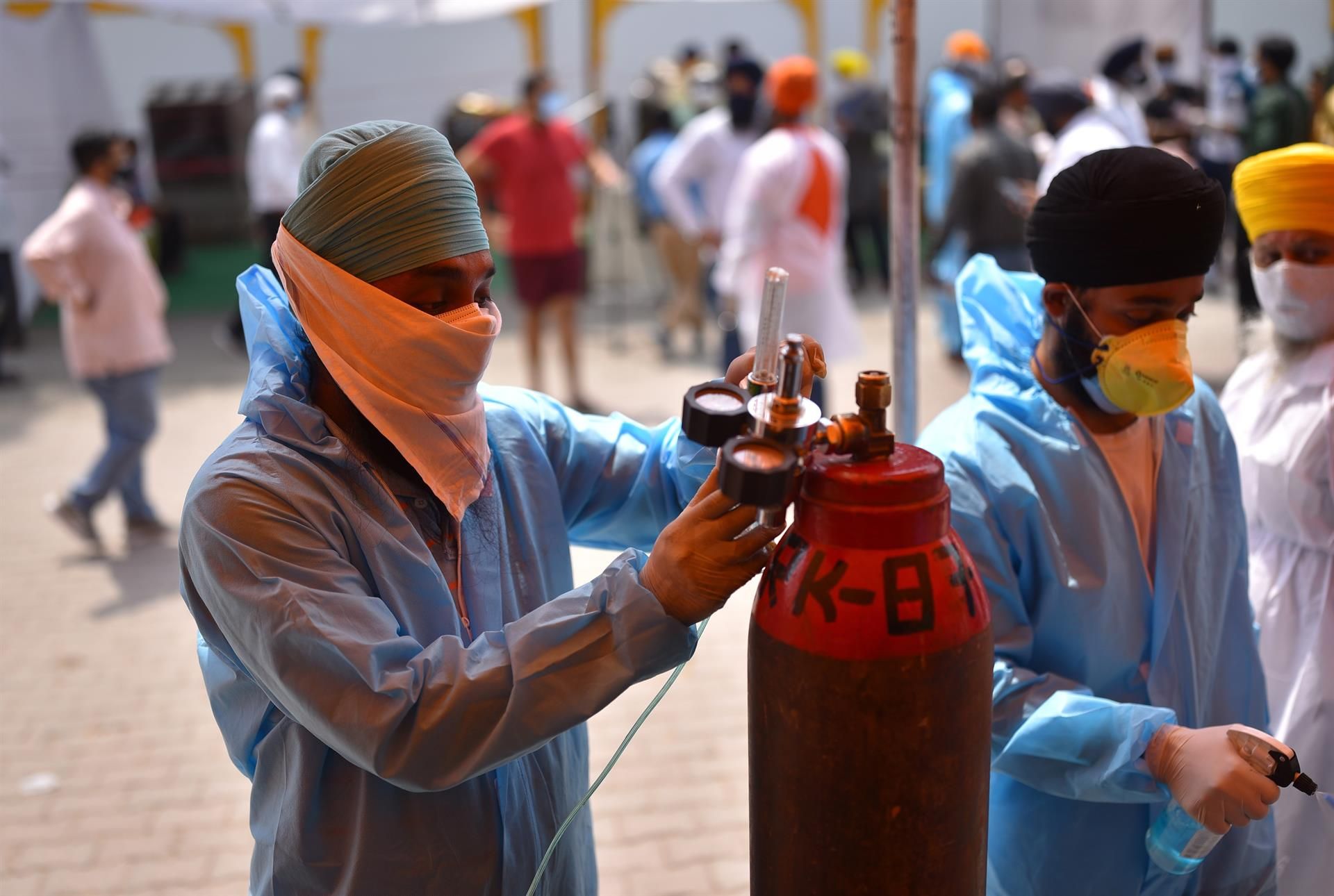 Un sanitario rellena una bombona de oxígeno en un puesto de atención médica en Nueva Delhi.