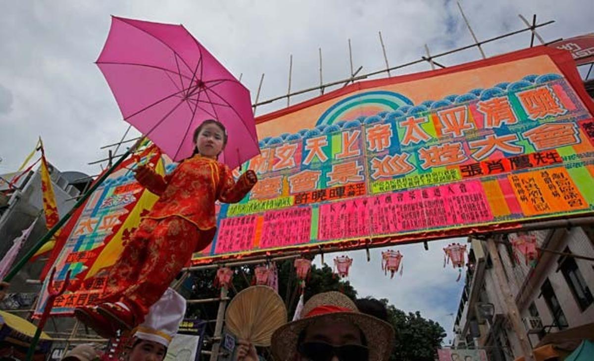 Una nena fa equilibris sobre un pal durant la processó del Festival Bun, en honor al déu taoista del mar, a l’illa de Cheung Chau (Hong Kong).