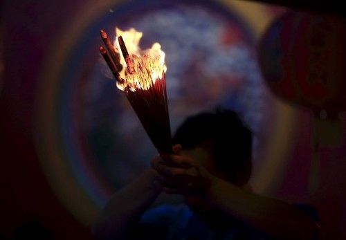 A man prays for good fortune while holding incense on the first day of the Chinese Lunar New Year at Petak Sembilan Temple in Jakarta