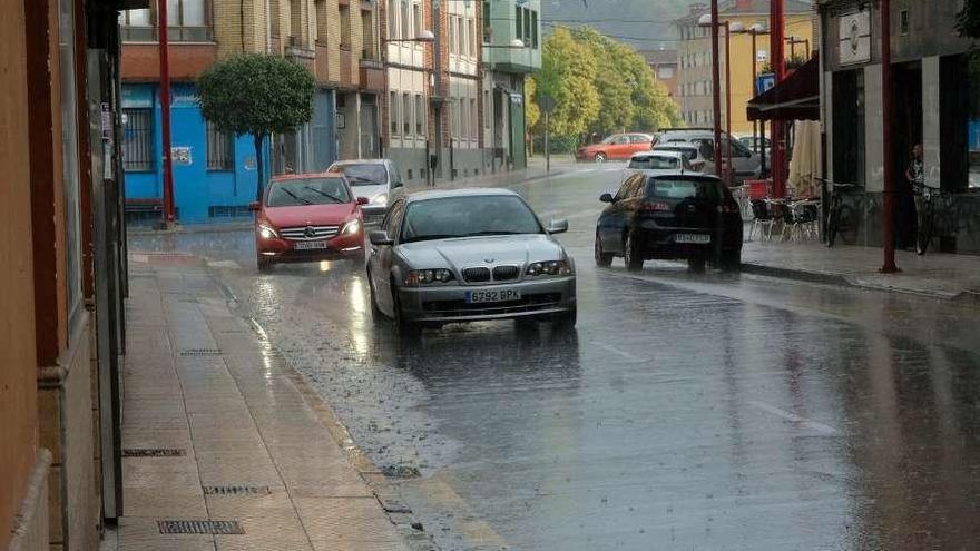 La calle Pelayo de Pola de Laviana, ayer, durante una tormenta, con agua acumulada en la calzada.