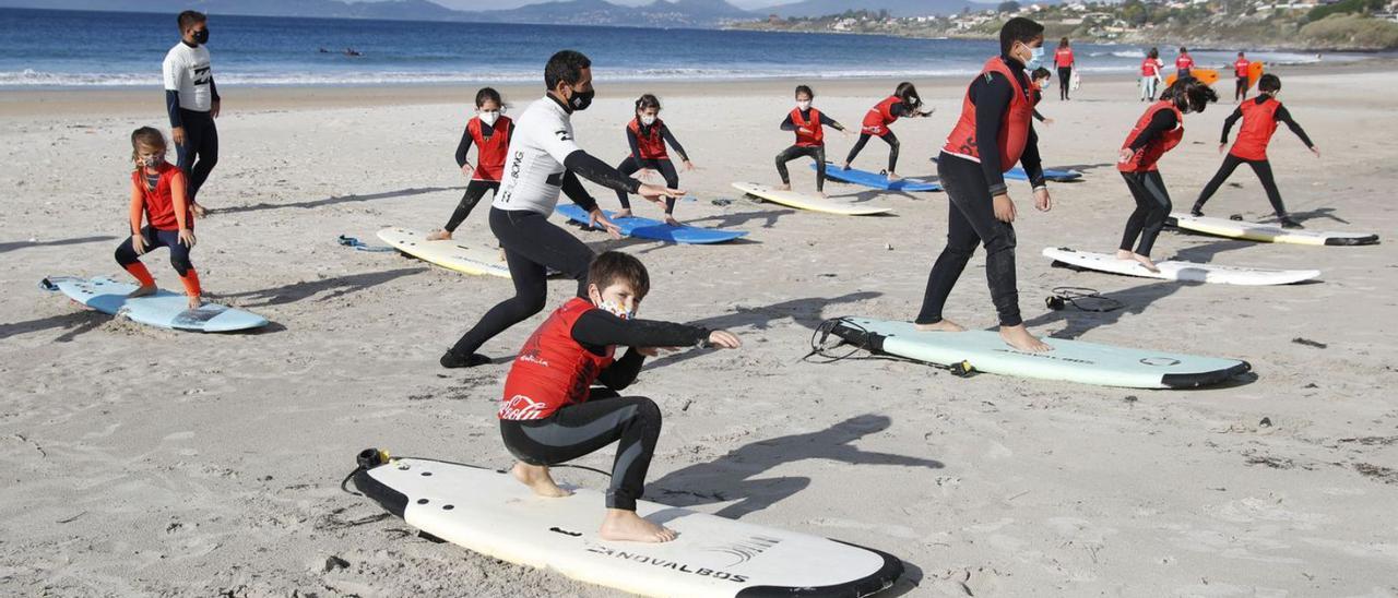 Niños en una clase de surf del Patos Surf Club en el arenal nigranés.   | // RICARDO GROBAS