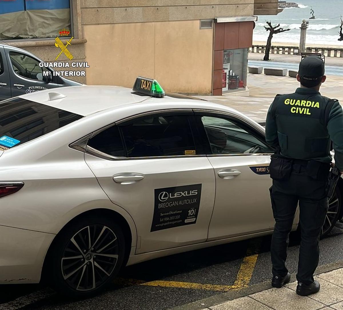 Un guardia civil junto a un taxi.