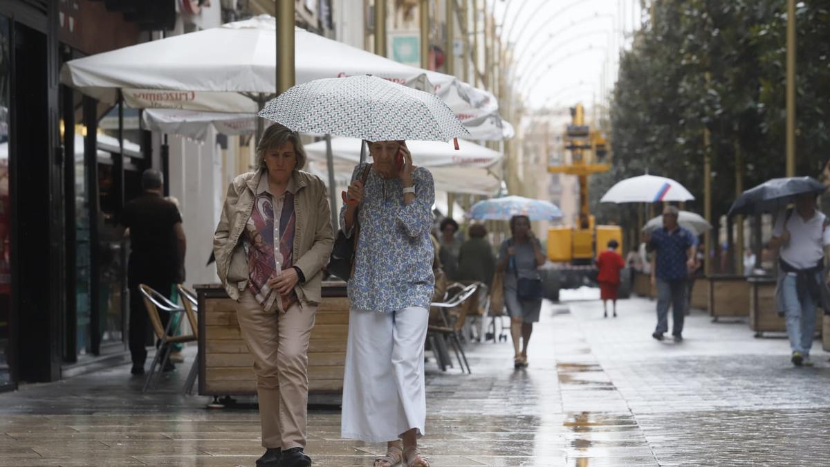 Dos mujeres se protegen de la lluvia con paraguas.