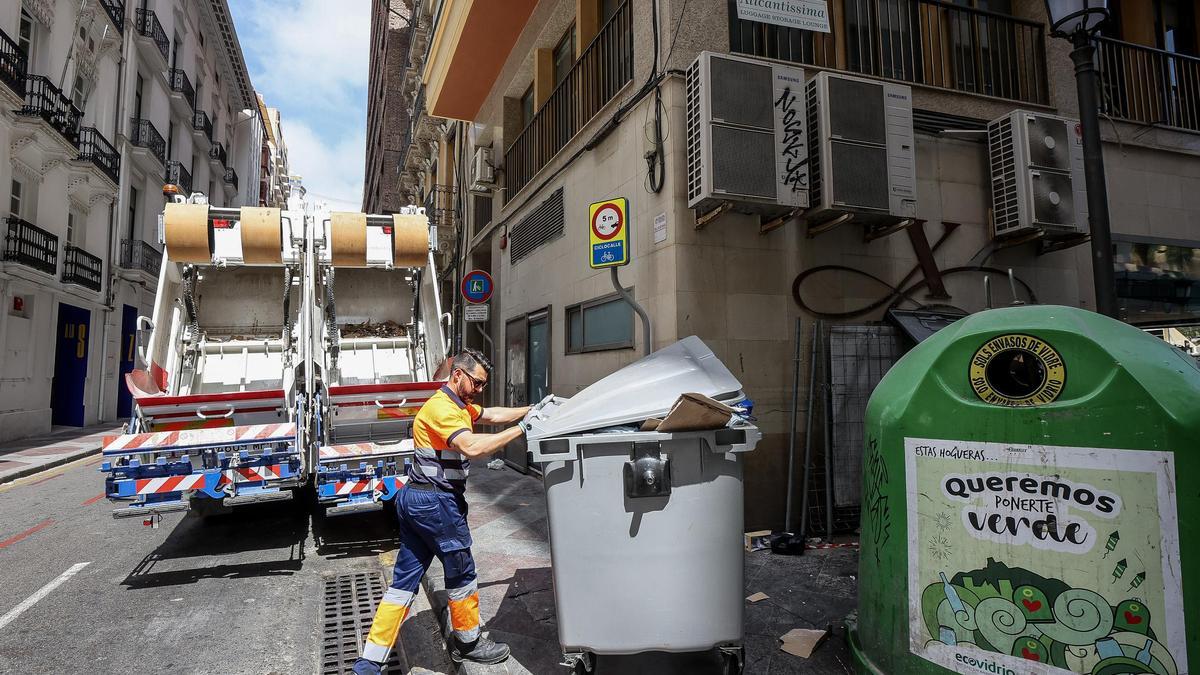 Retirada de un contenedor de resto, situado junto a un iglú de vidrio en Alicante.