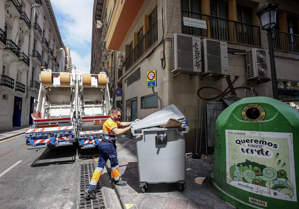 Retirada de un contenedor de resto, situado junto a un iglú de vidrio en Alicante.
