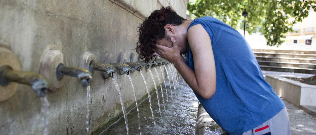 Un joven se refresca en la «Font dels 25 Dolls» de Xàtiva, en una imagen reciente. | PERALES IBORRA