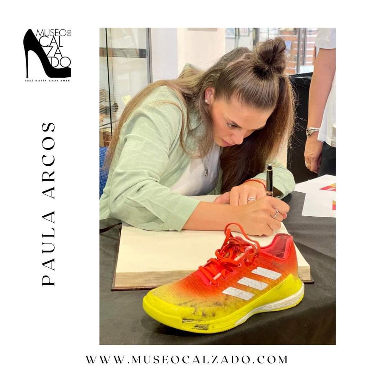 Paula Arcos firmando en el Libro de Honor del Museo del Calzado con la zapatilla que ha donado.