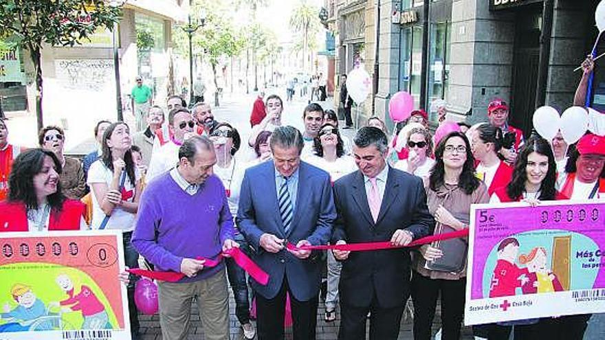 Arriba, Quini, Manuel Vega-Arango y José Luis Carmona, en el corte de cinta que da inicio a la campaña. A la derecha, voluntarios y vendedores de papeletas  de la Cruz Roja. /