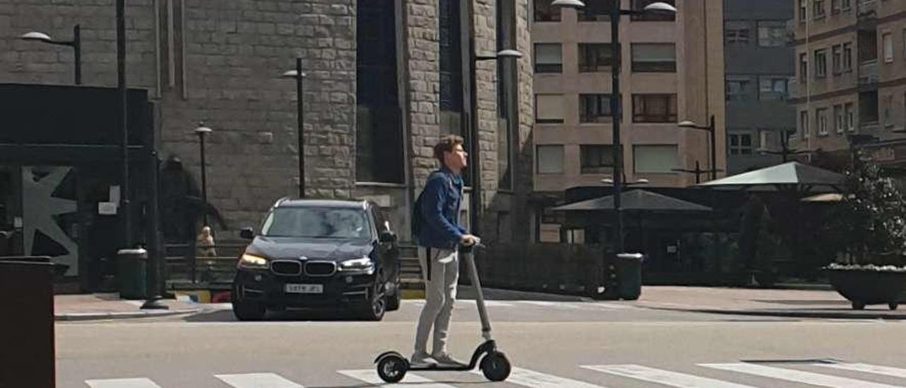 Un joven cruzando un paso de peatones con un patinete eléctrico en la calle Federico García Lorca.