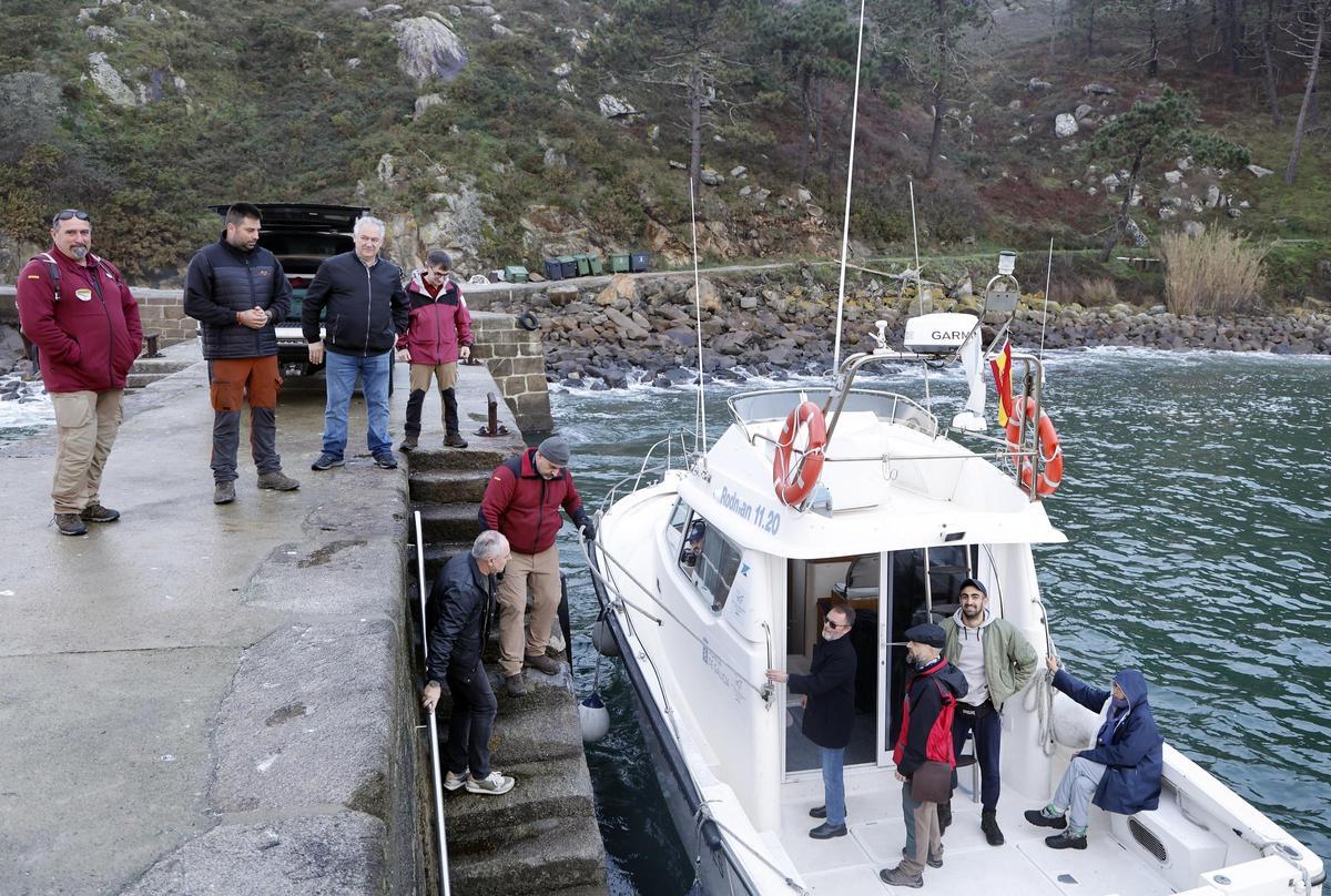 Agentes y vigilantes forestales, técnicos, científicos y operarios de Tragsa en un cambio de turno (habitualmente semanal) en el muelle de la Punta de Carracido