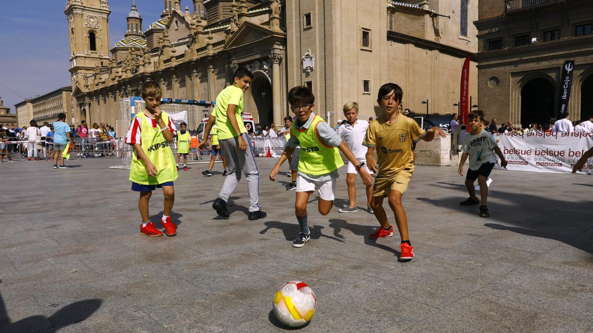 Unos niños juegan a fútbol esta mañana en la plaza del Pilar.