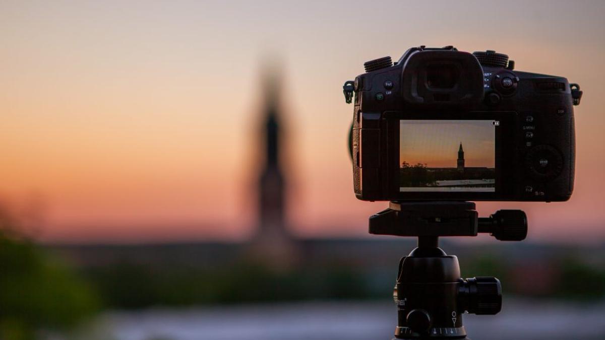 Una cámara fotográfica en su trípode capta una una puesta de sol.
