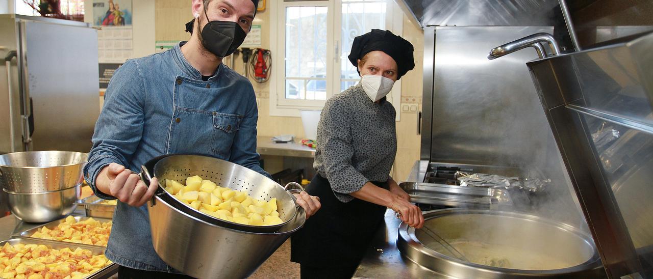 Moisés Rodríguez y Trini Pérez preparan el caldo de gloria en la cocina del colegio Salesianos.