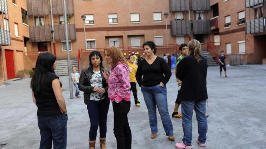 Varias de las madres afectadas, con un grupo de niños, detrás, jugando en el patio del barrio.