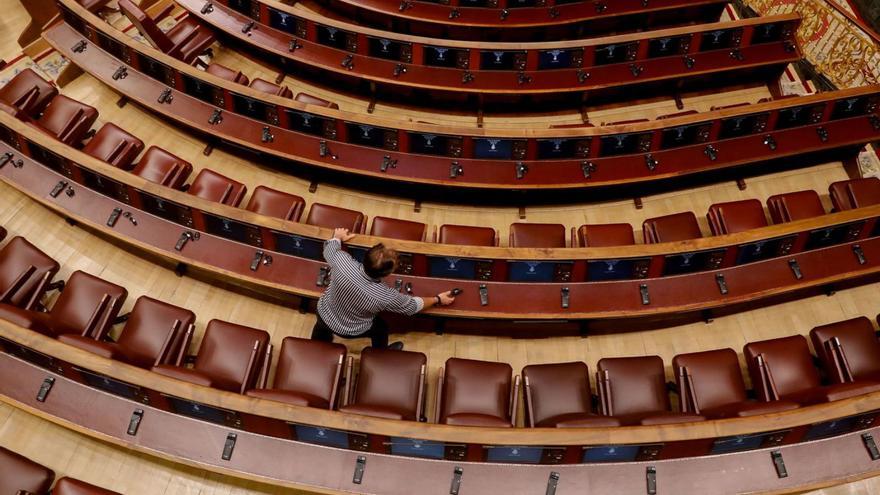 Un técnico coloca los auriculares en los asientos del Congreso, antes de una sesión reciente. |