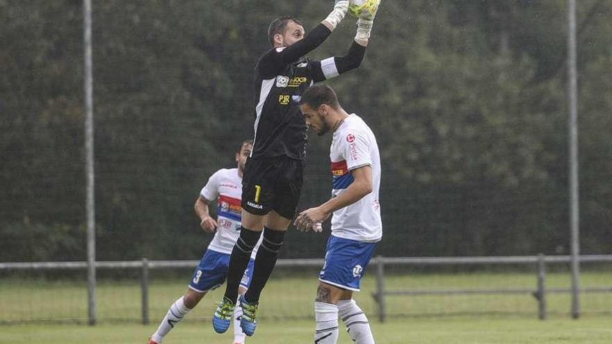 El portero langreano Adrián Torre atrapa un balón en el partido contra el Vetusta en El Requexón ante Alain, con Ander Gayoso, al fondo.