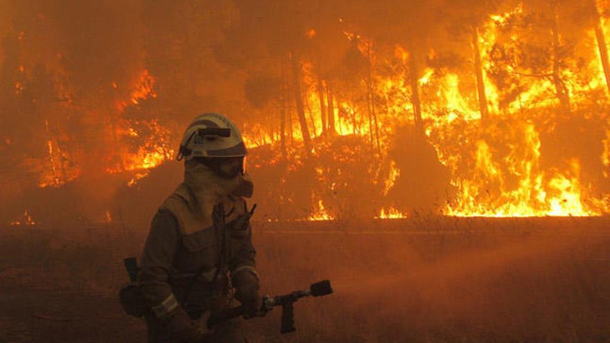 Un efectivo combate las llamas de un incendio en Santiago. // X. Rey