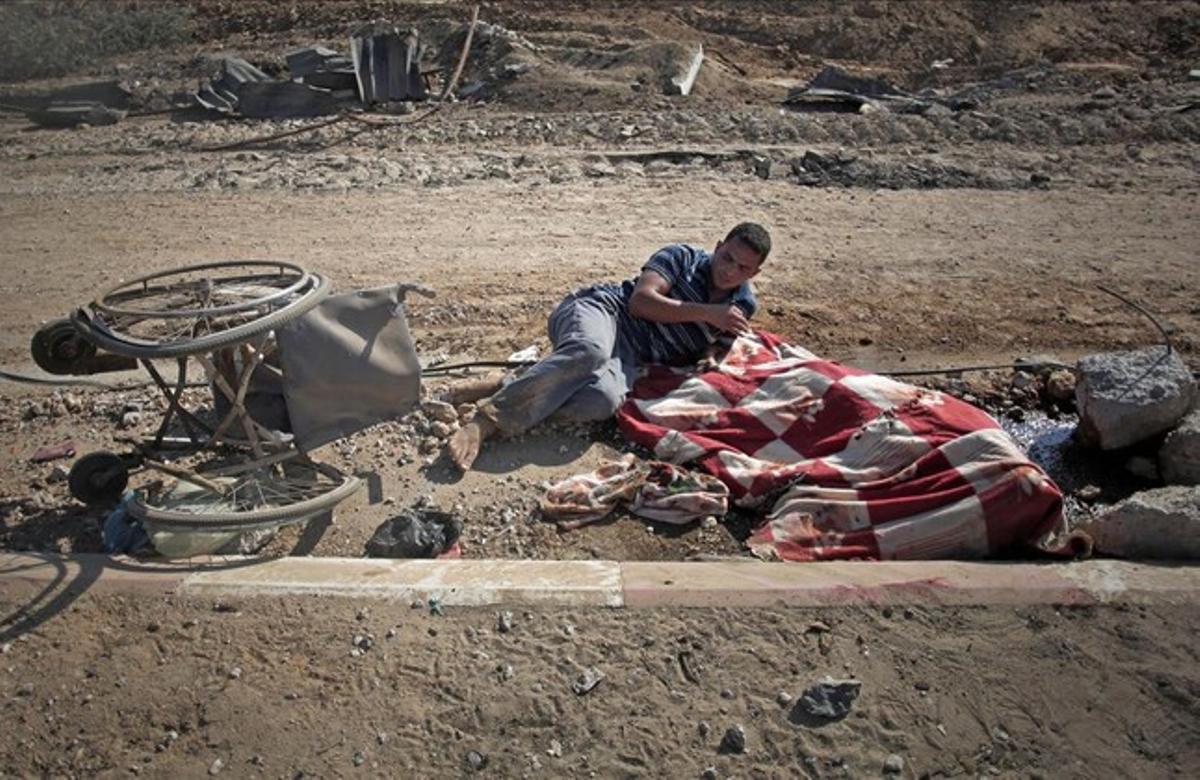 El palestino Nidal Abu Rjeilah, junto al cadáver de su hermana Gadir de 17 años, cubierto con una manta.