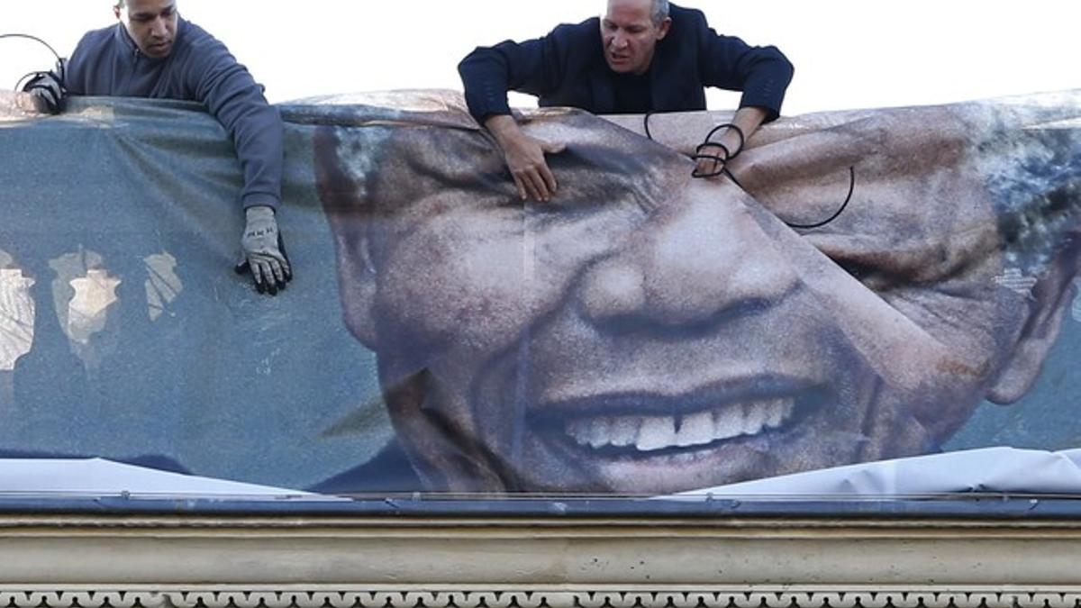 Dos hombres despliegan, el viernes, un mural con el rostro de Mandela que cubre la fachada del Ministerio de Asuntos Exteriores francés, en París.