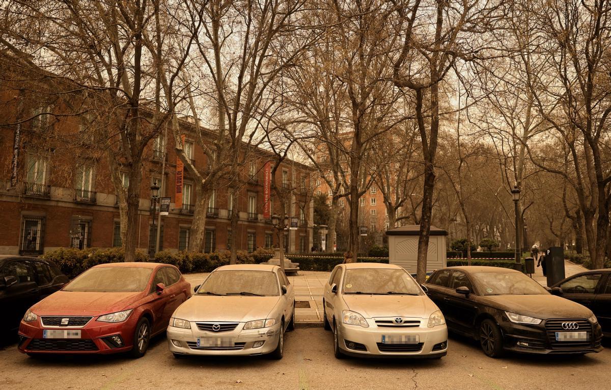 Una fila de vehículos cubiertos de polvo subsahariano, en Madrid.