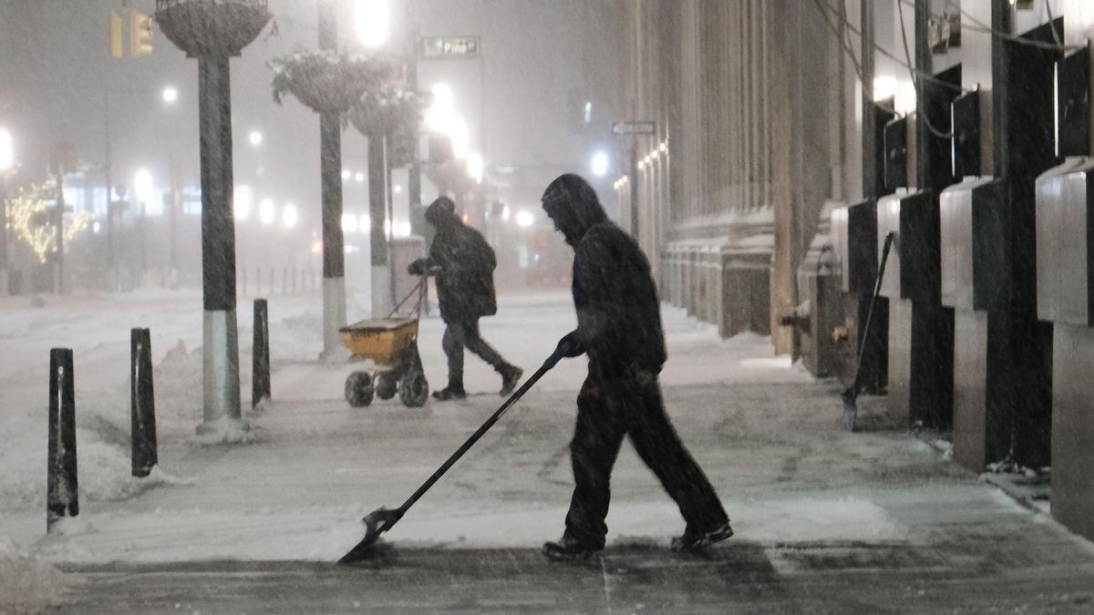 Un hombre limpia la nieva de la acera en el Lower Manhattan 