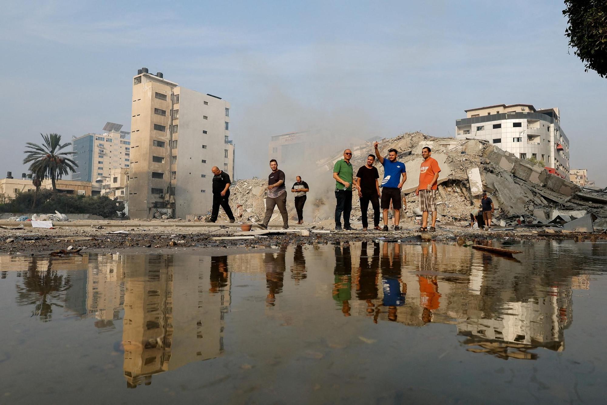 Palestinos inspecciona las ruinas de la torre de Al-Watan, en Gaza, destruida por los ataques israelís,