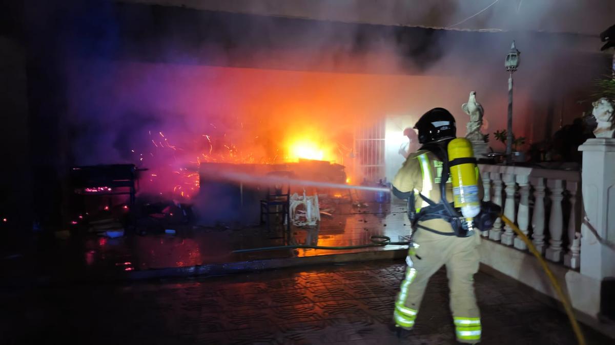 Un bombero apaga las llamas del incendio en el patio de la vivienda de Molina.