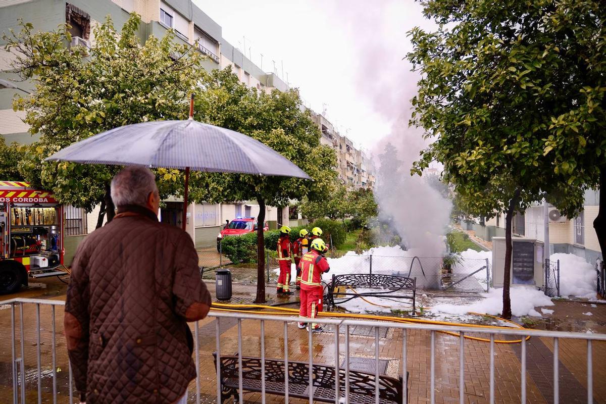 Los bomberos extinguen el incendio ante la mirada de un vecino.