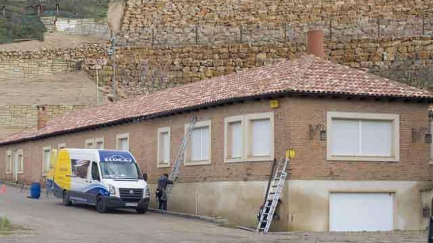 Un electricista coloca una escalera en la fachada de la vivienda precintada tras el desplome de los cuestos.