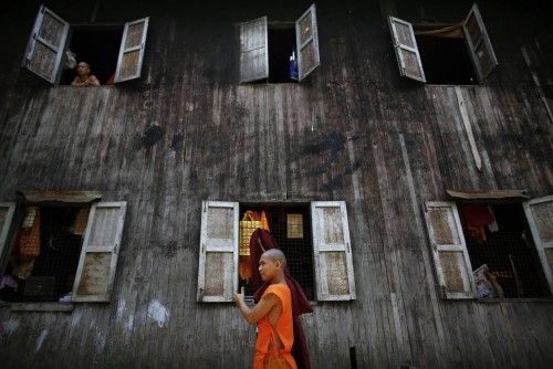 An ethnic Shan Buddhist monk carries his robe as another looks out the window of their monastery in Yangon