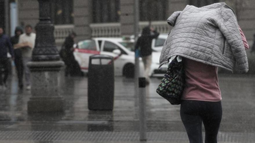 Una dona que tapa amb un abric pel temporal de pluja