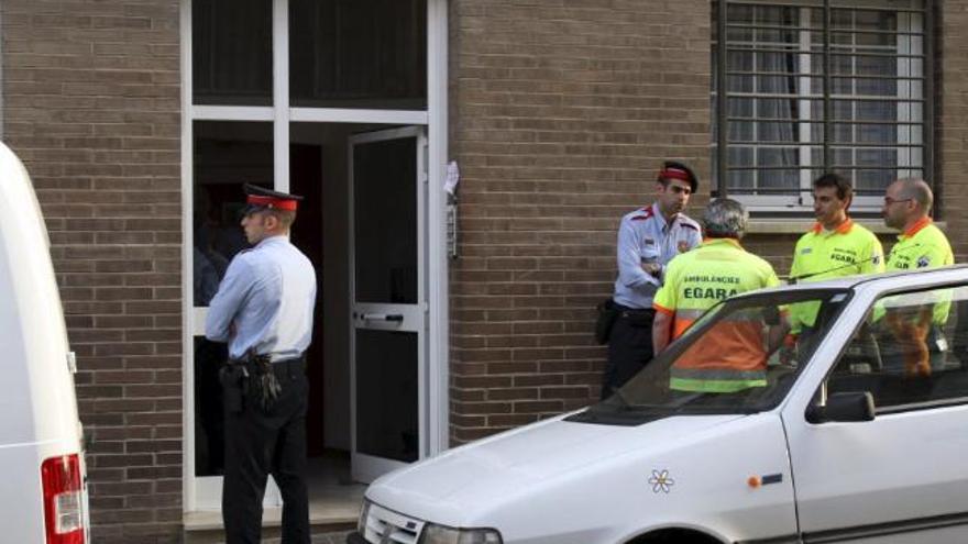 Dos policías y varios miembros de los sevicios de Emergencias conversan a las puertas de inmueble de la calle Gustavo Adolfo Bécquer del barrio de Can Rull en Sabadell, donde hoy un hombre ha tiroteado mortalmente a su ex mujer y después ha sido encontrado gravemente herido tendido junto a la víctima del homicidio. El hombre se ha intentado suicidar tras disparar y matar a la mujer, al parecer justo al día siguiente de haber firmado el divorcio.