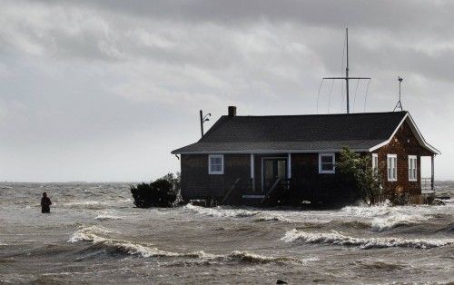 A man walks away from a building that has been surrounded by water pushed up by Hurricane Sandy in Bellport, New York