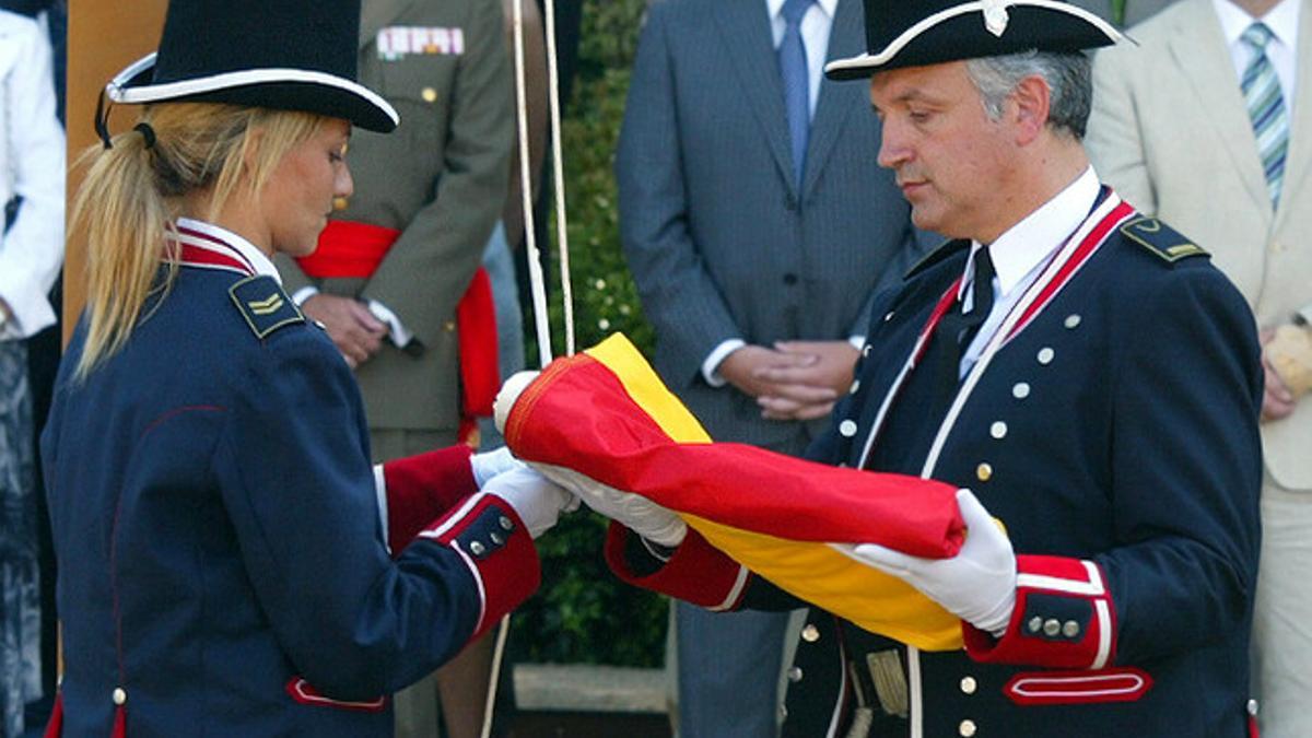 Dos mossos de gala doblan la 'senyera' durante la Diada.