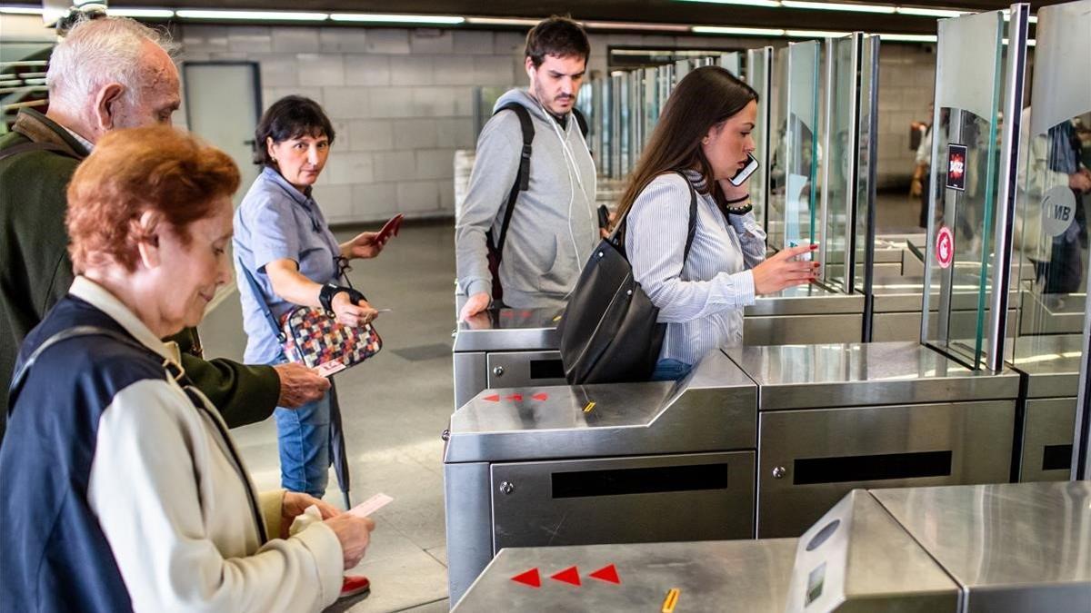 Unos usuarios del metro validan sus billetes, esta mañana