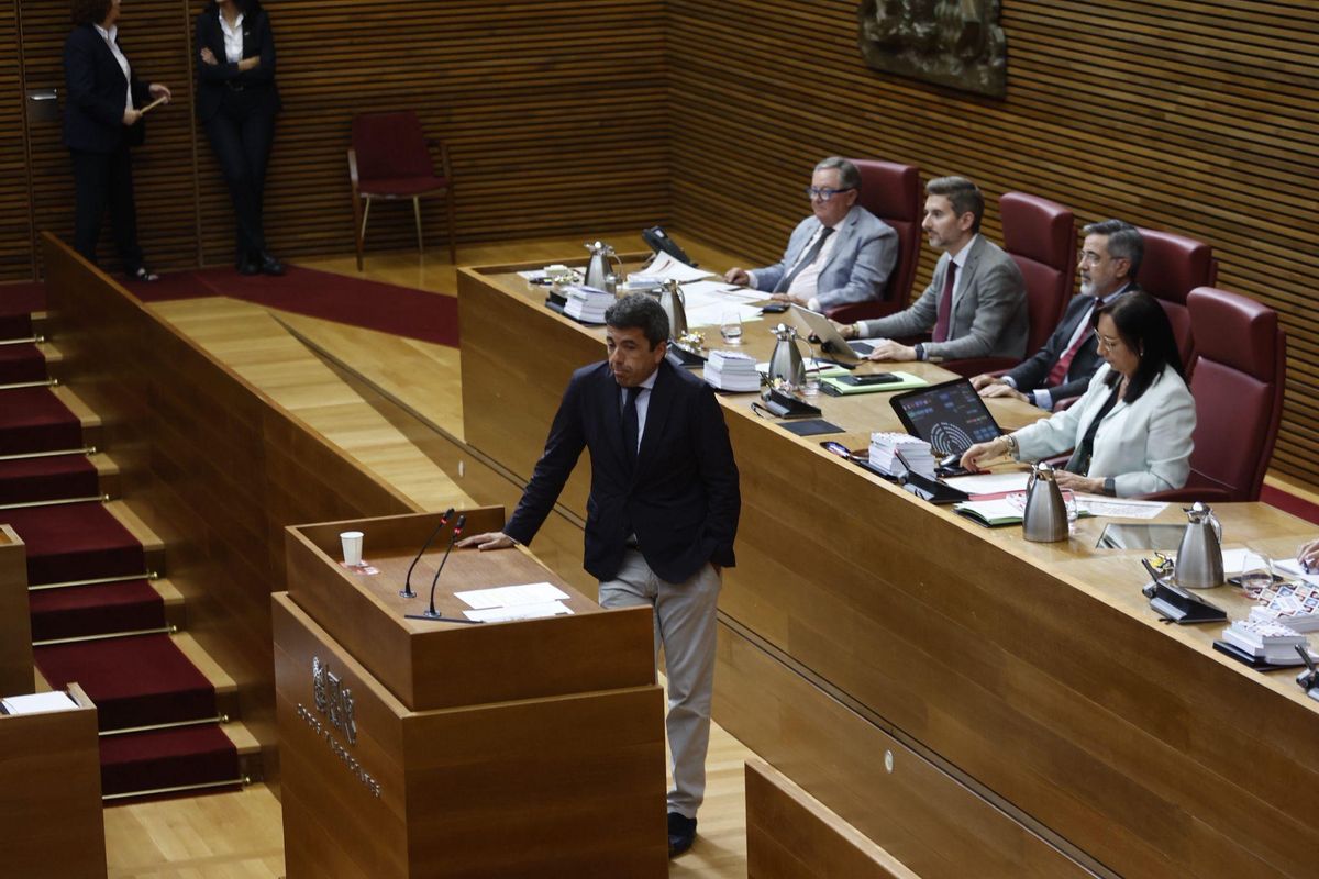 Mazón espera en la tribuna mientras los diputados de Compromís protestan.