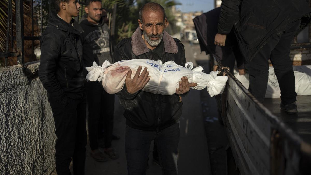 Un hombre porta el cuerpo sin vida de su nieto muerto por un bombardeo israelí, este viernes en el hospital de Rafah, al sur de Gaza.
