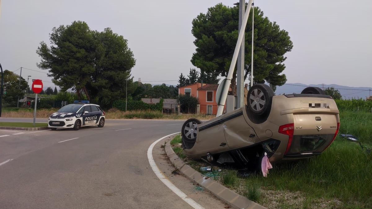 Turismo volcado en una rotonda, tras estrellarse.