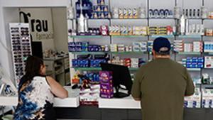 Dos clients esperen a ser atesos en una farmàcia.