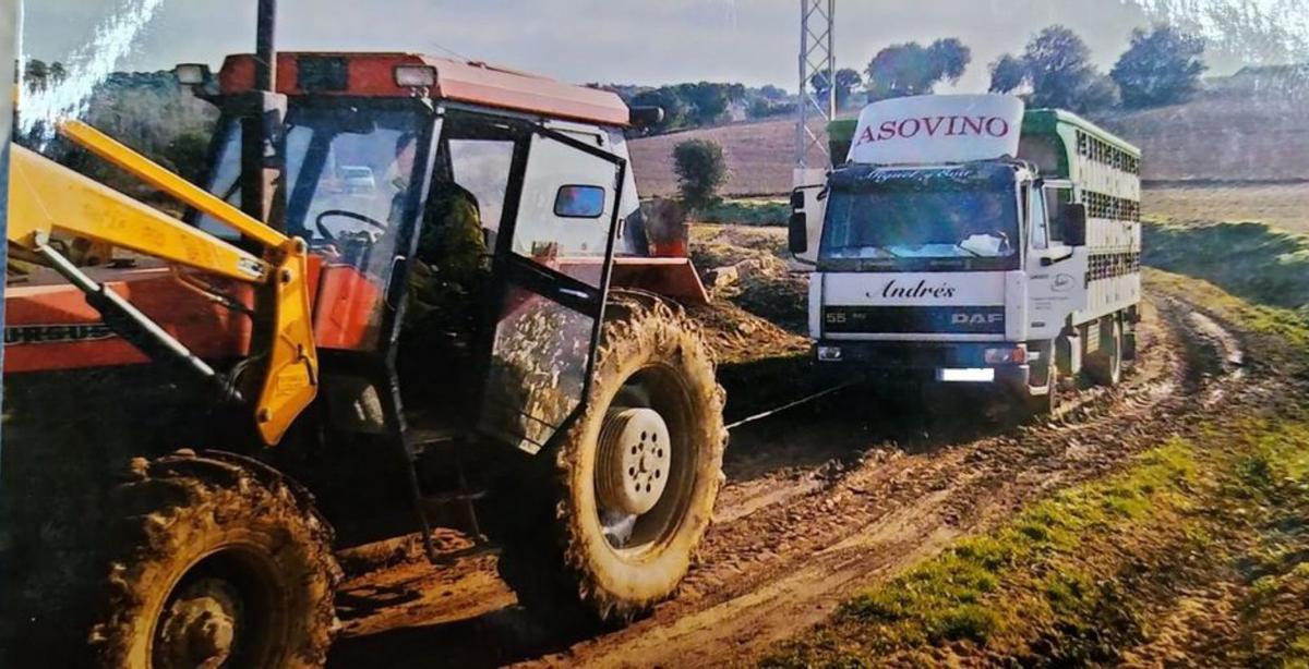 Un tractor tira de un vehículo atascado el camino a la dehesa. | Cedida