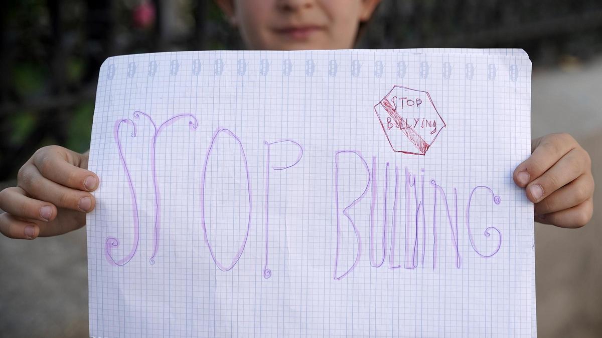 Un niño sostiene un cartel con el lema 'Stop the bullyng'.