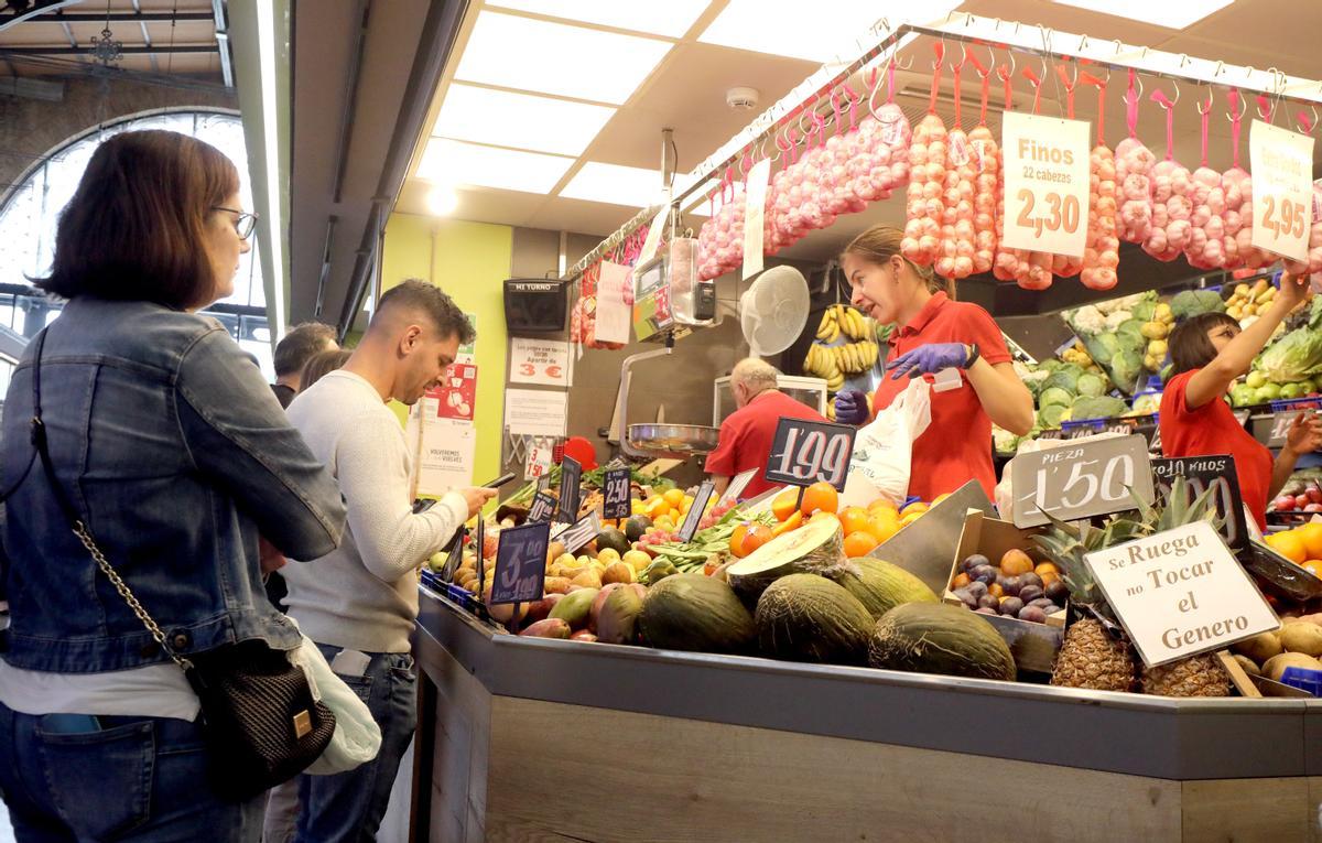 Varios clientes esperan su turno en un puesto de frutería.