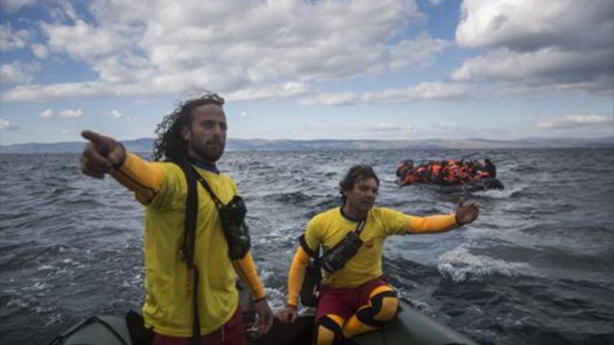 Dos miembros de Proactiva Open Arms socorren a refugiados en el Egeo.