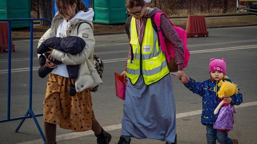 Una joven madre ucraniana y sus dos hijos cruzan la frontera con Rumanía ayudados por una voluntaria. | JAVI PAREJO
